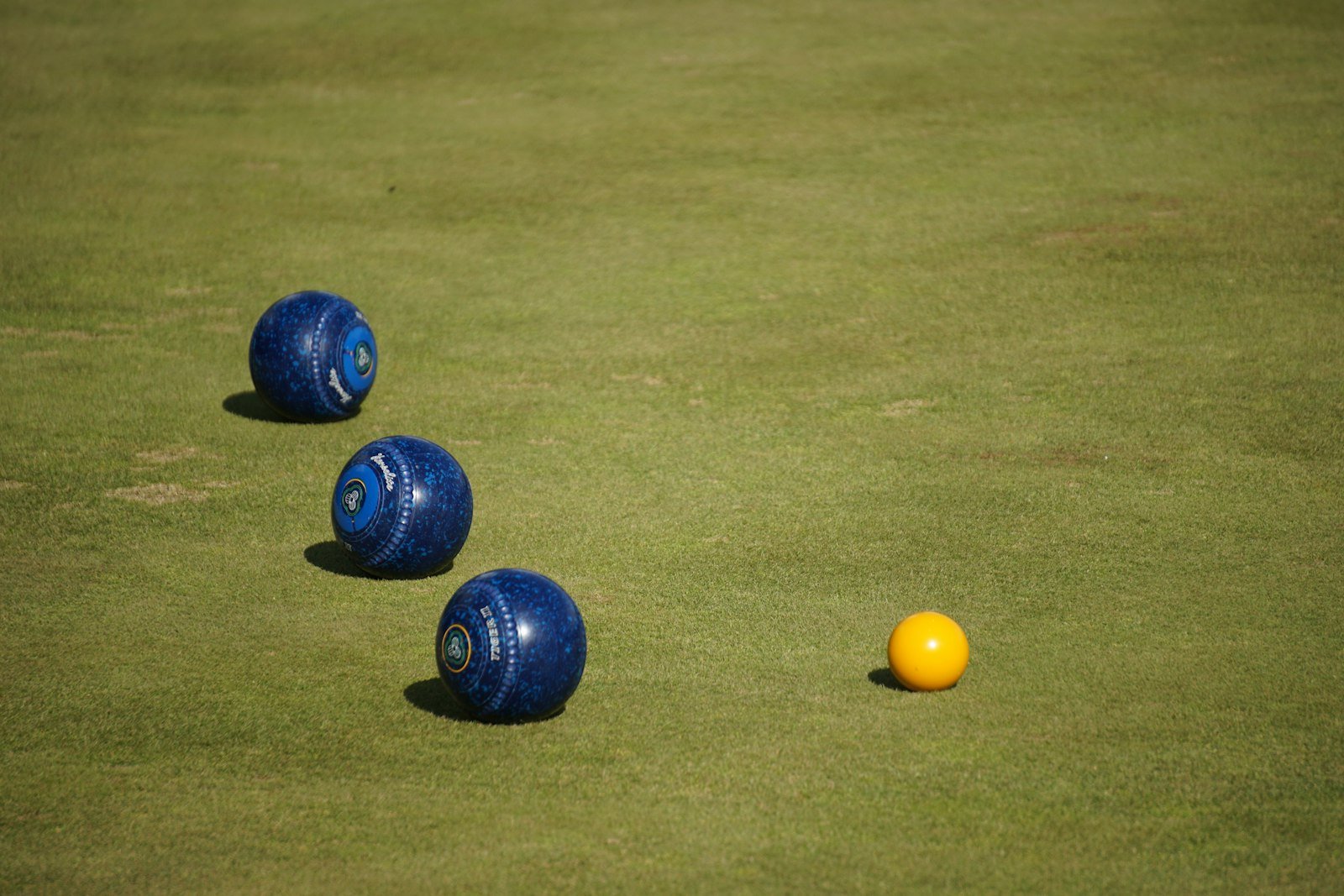 Three lawn bowls close to the jack on a green